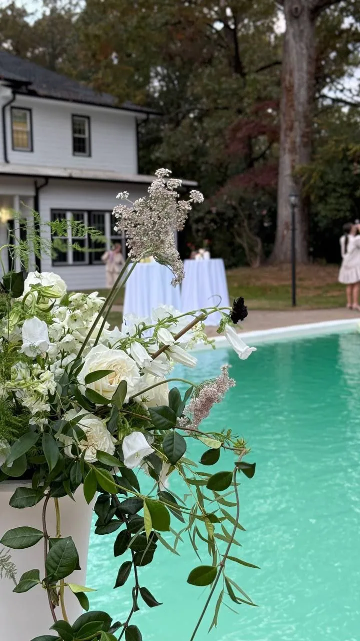 White wedding floral arrangement by the swimming pool in front of WestWind Estate in Spartanburg SC