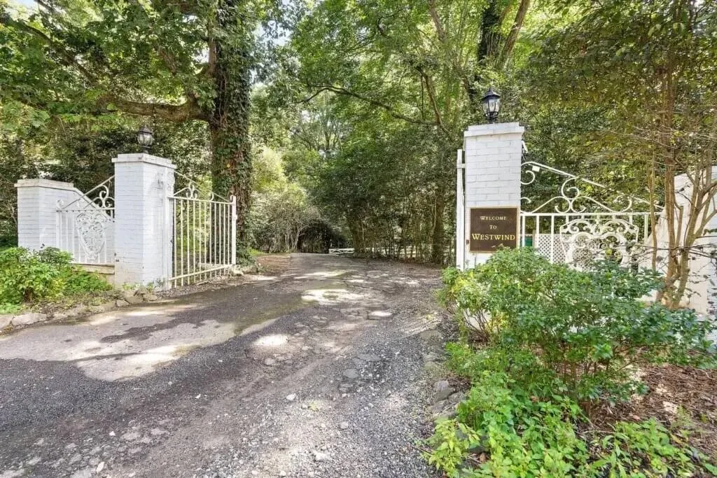 White iron gates and tree-lined drive welcoming guests to WestWind Estate, a secluded and elegant wedding venue in Upstate South Carolina.